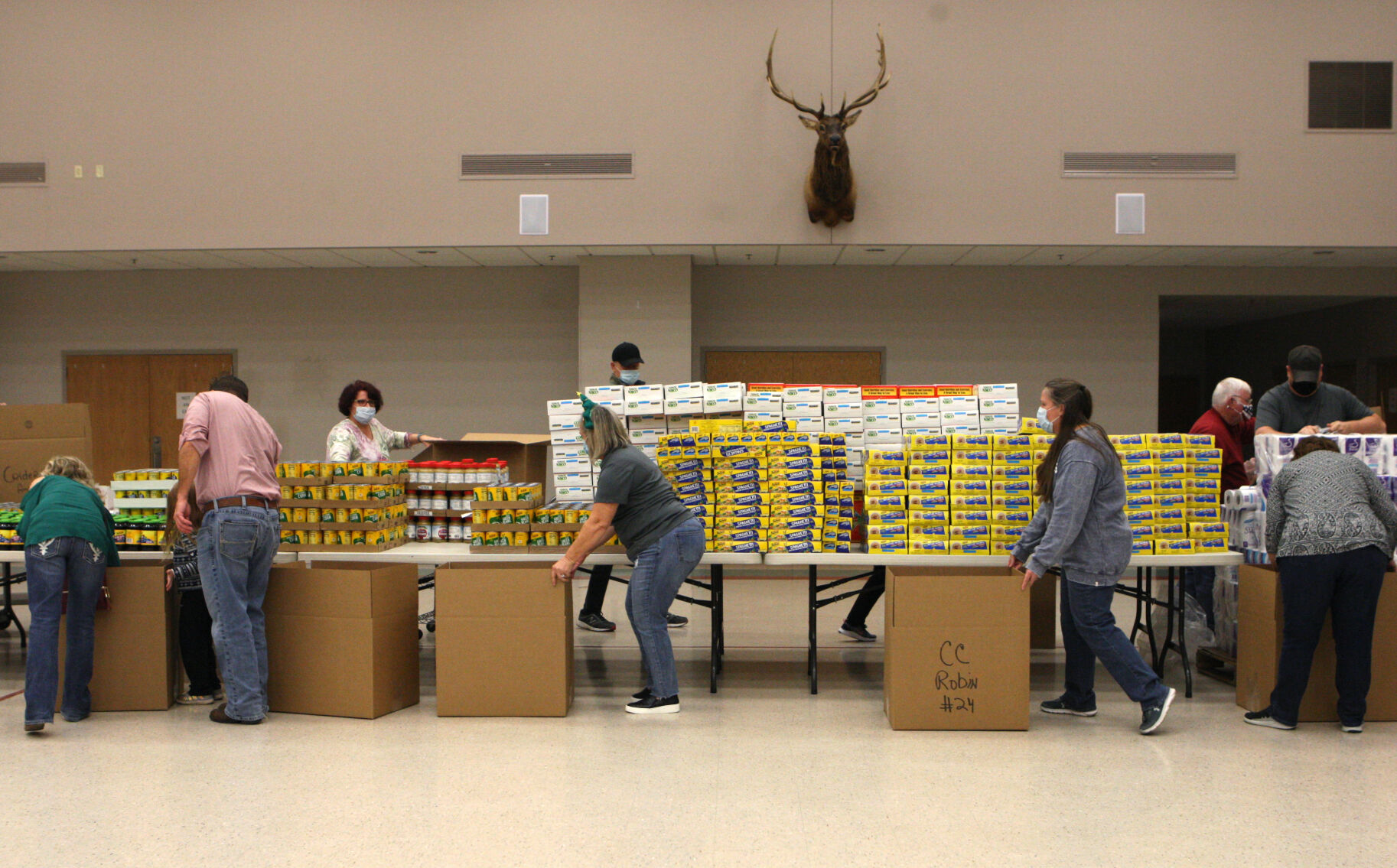 Volunteers circle a table of grocery items